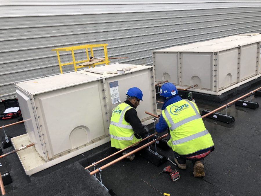 Two engineers running copper pipework to rooftop plant